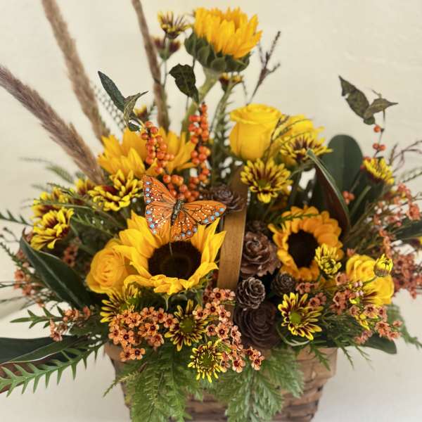 Autumn flower basket with sunflowers, yellow roses, and an orange butterfly accent