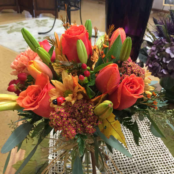 Orange roses and tulips arranged in a glass vase