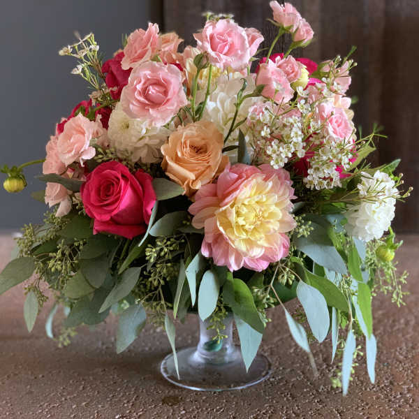 Mixed pink and peach flower arrangement in a clear glass vase