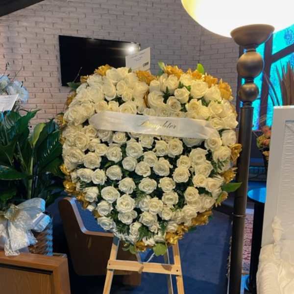 Heart-shaped white rose arrangement on an easel with gold accents