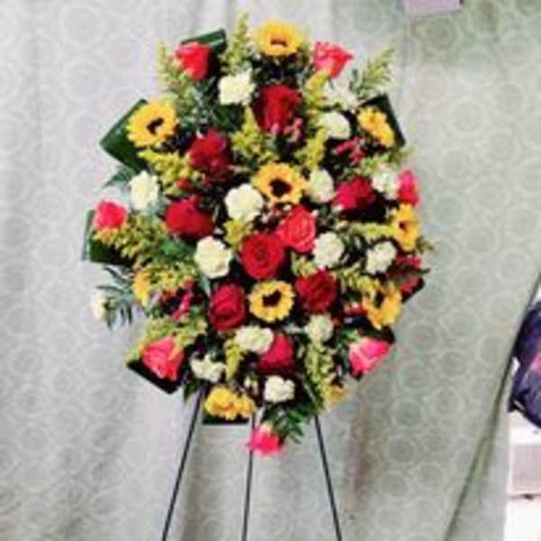 Colorful standing floral spray with roses and daisies on a black easel