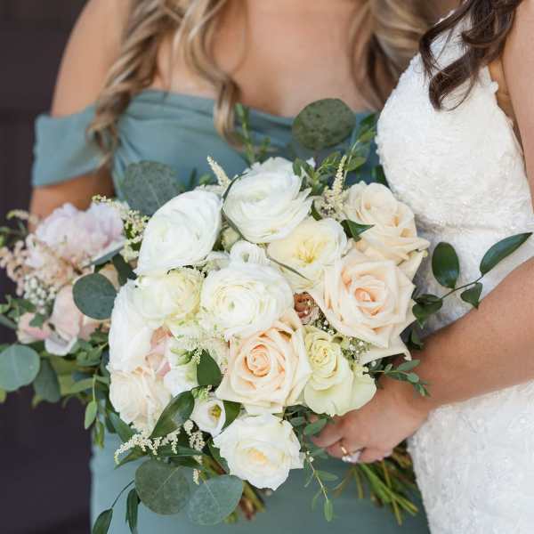 Bride and bridesmaid holding white and blush rose bouquets