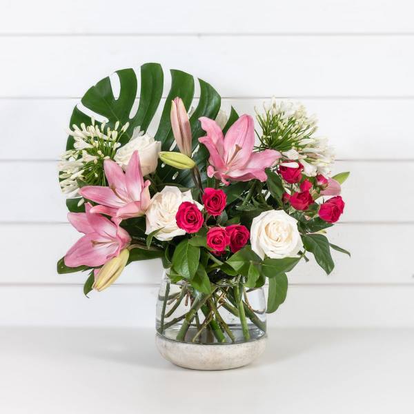 Pink lilies and roses arranged in a glass vase