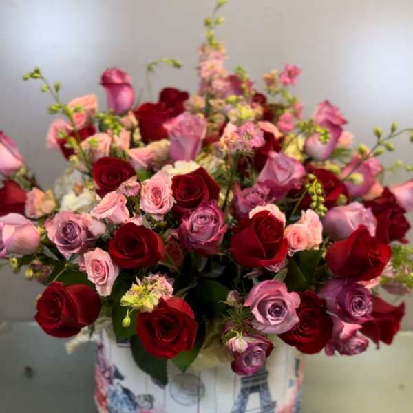 Bouquet of red, pink, and lavender roses in a decorative round box