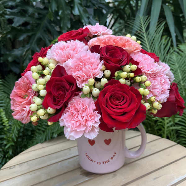 Pink and red flower bouquet in a mug with heart decorations