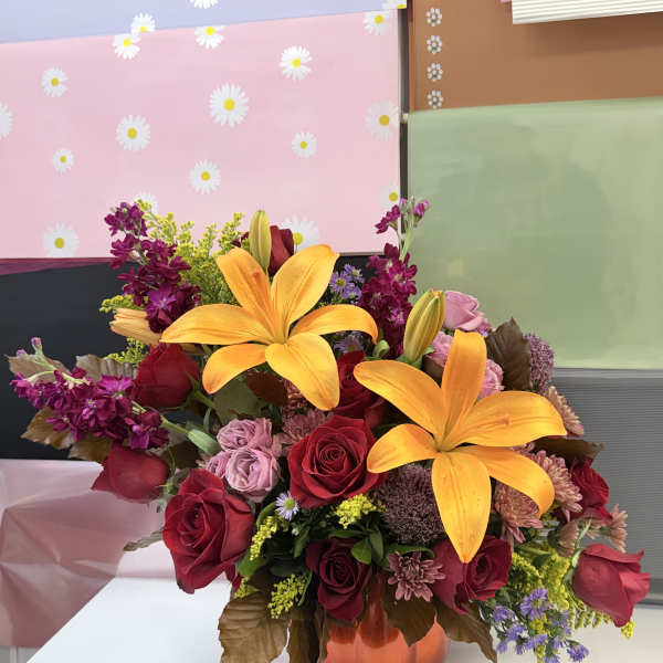 Mixed bouquet with orange lilies and red roses in an orange vase