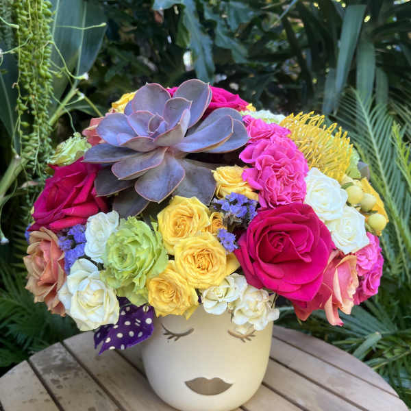 Colorful bouquet with roses and a large succulent in a face vase