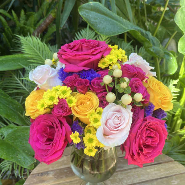 Mixed bouquet of pink, yellow, and white roses in a glass vase