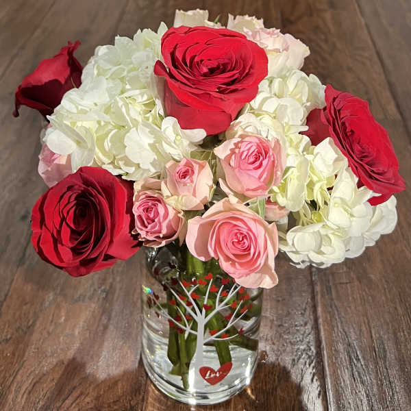 Bouquet of red, pink, and white roses in a clear glass vase