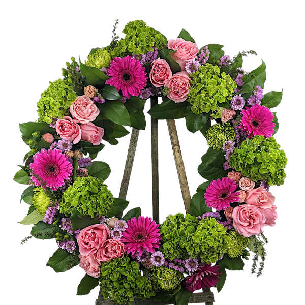 Floral wreath of pink roses, magenta daisies, and green hydrangeas on an easel