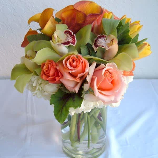 Bouquet of orange roses and calla lilies in a clear glass vase