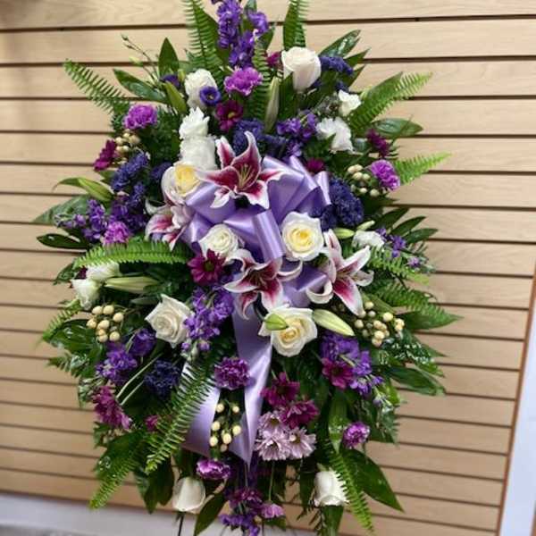 Standing floral spray with purple and white flowers on a metal easel