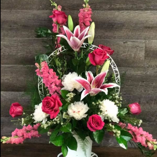 Pink and white floral arrangement in a white vase with a decorative frame