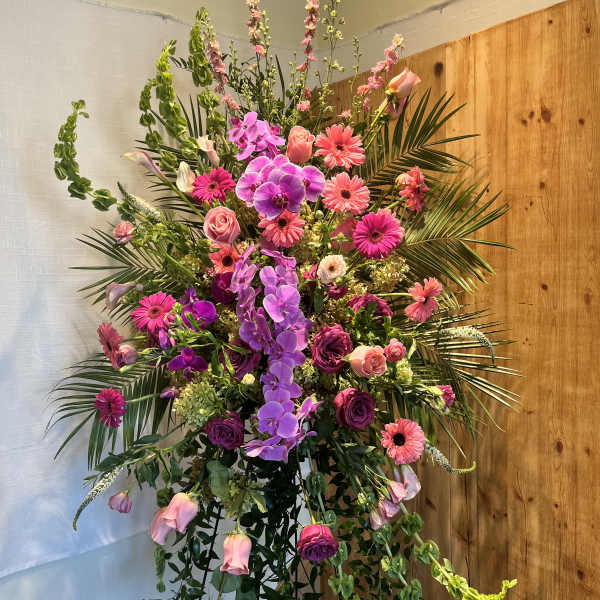 Tall floral arrangement with pink and purple blooms in a stand