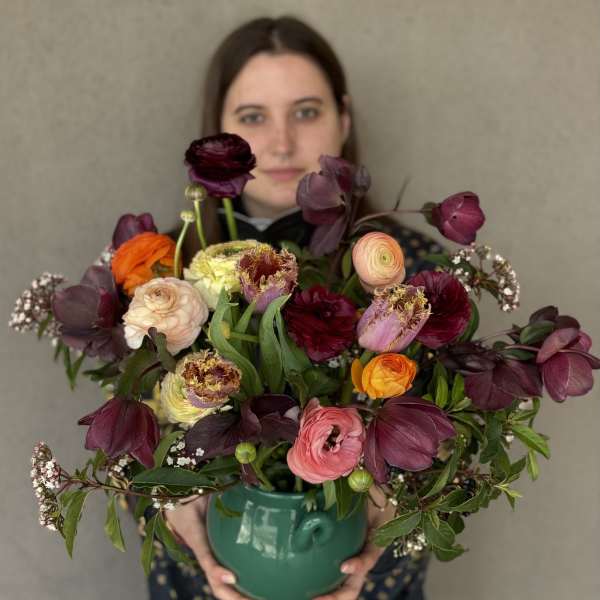 Mixed bouquet in a green ceramic vase with burgundy, pink, orange, and cream blooms