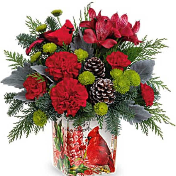 Red floral arrangement in a decorative vase with pinecones and greenery