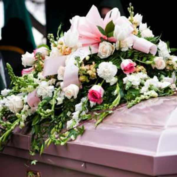 Pink and white floral casket spray on a mauve casket