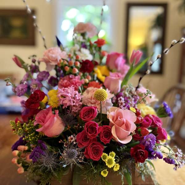 Colorful mixed flower arrangement in a wooden box with tall pussy willow stems