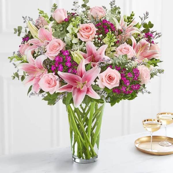 Pink roses and lilies arranged in a clear glass vase