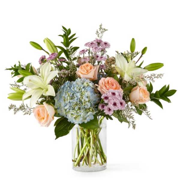 Bouquet of lilies, roses, and hydrangea in a clear glass vase