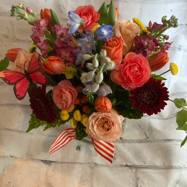 Mixed bouquet of colorful flowers with a striped ribbon and butterfly decoration
