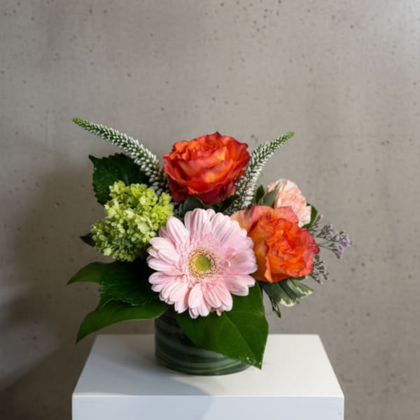 Small bouquet of orange roses and a pink gerbera daisy in a glass vase