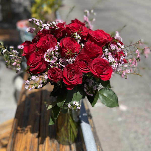 Bouquet of red roses with small pink filler flowers in a glass vase