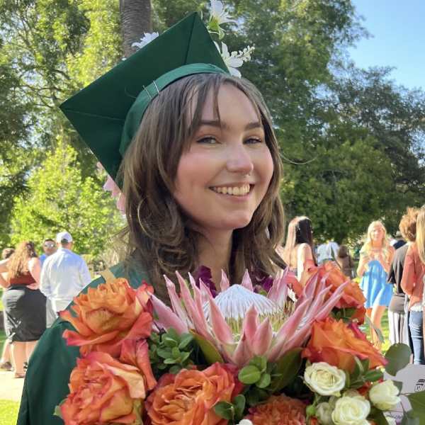 Graduate holding a bouquet of orange and white flowers