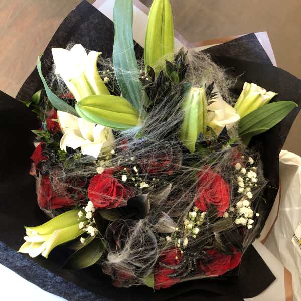 Bouquet of red roses and white lilies wrapped in black paper