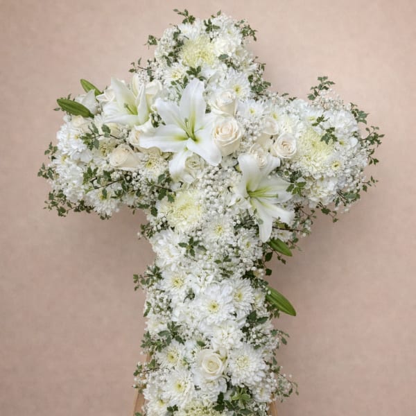 White floral cross arrangement on a wooden easel