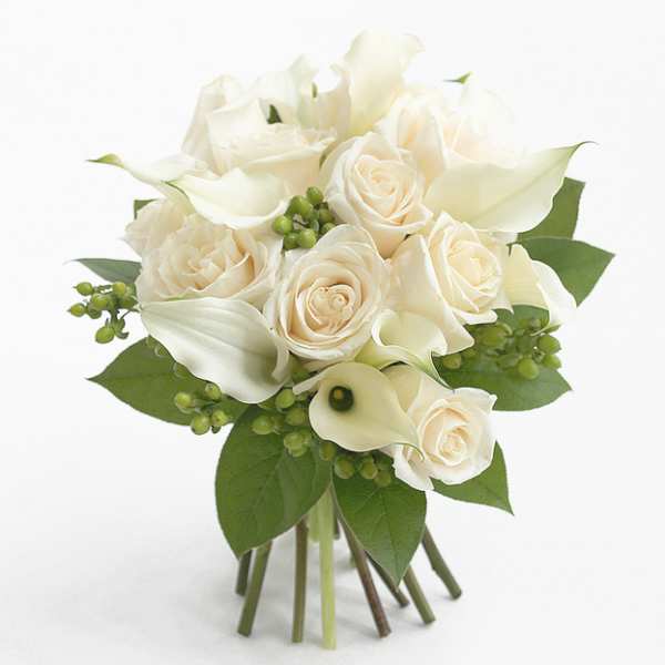White roses and calla lilies arranged with green berries