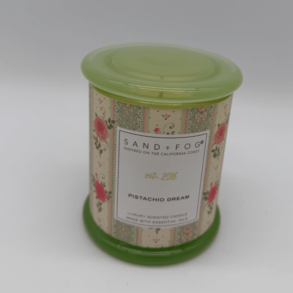 A floral-patterned scented candle in a green tin container