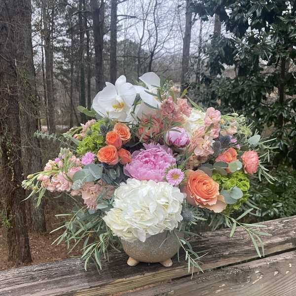 Mixed bouquet in a stone vase with white orchids and pink, peach, and white blooms