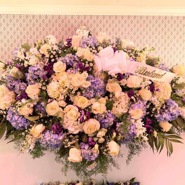 Large pastel floral spray with roses, hydrangeas, and a pink ribbon