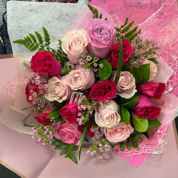 Bouquet of pink, lavender, and white roses wrapped in pink paper