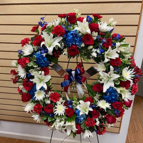 Large red, white, and blue floral wreath on a stand with ribbon