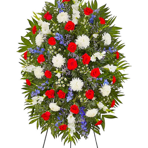 Standing floral spray with red roses, white blooms, and blue accents