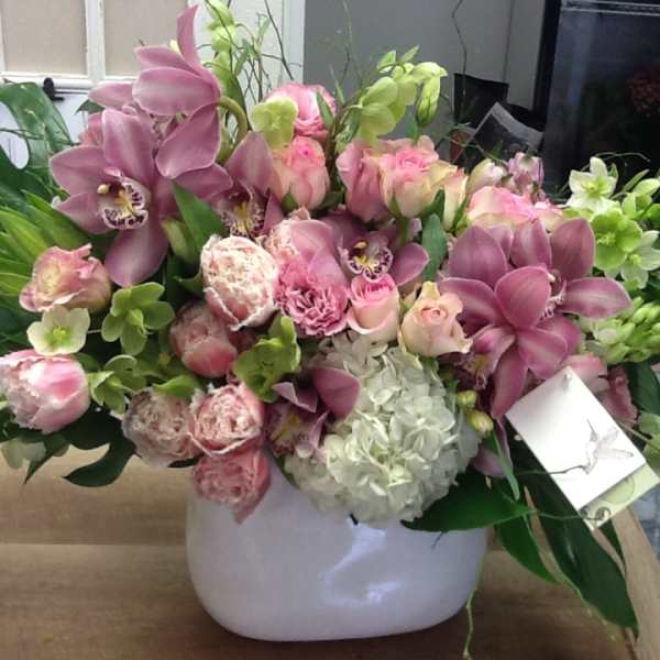 Pink orchids and roses arranged in a white vase