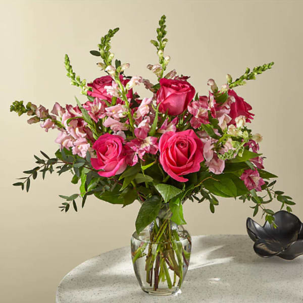 Pink roses and mixed pink flowers in a clear glass vase