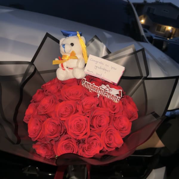 Bouquet of red roses with a small teddy bear and graduation sign
