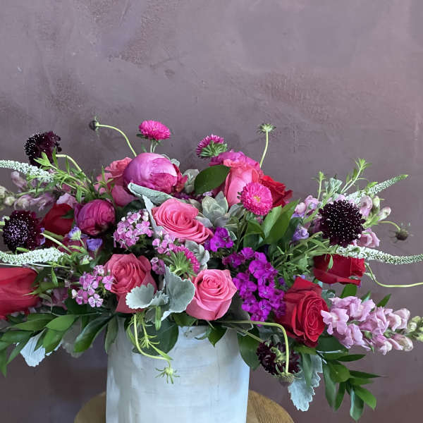Pink and red mixed flower arrangement in a white vase