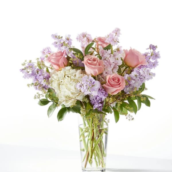 Pink roses and lavender flowers in a clear glass vase