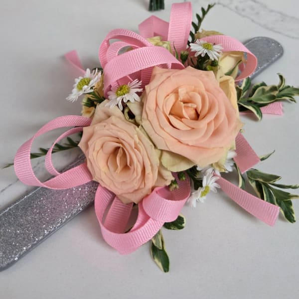 Peach rose corsage with pink ribbon and small white daisies