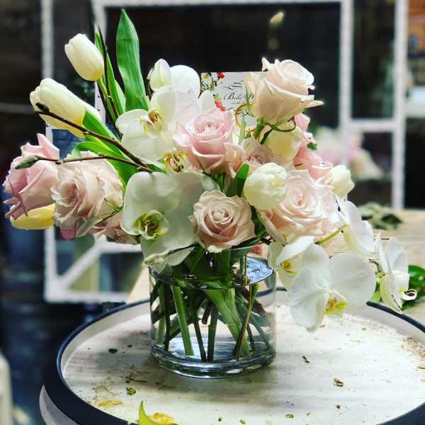 Bouquet of pale pink roses and white orchids in a clear glass vase