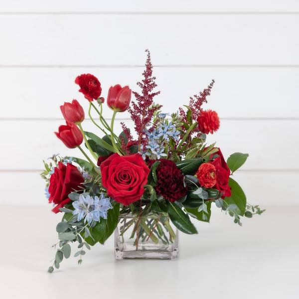 Red roses and tulips arranged in a clear square vase