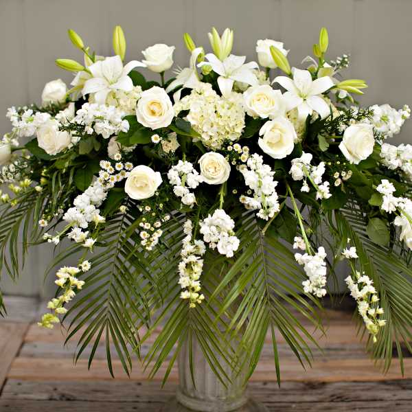 White floral arrangement with roses and lilies in a clear vase