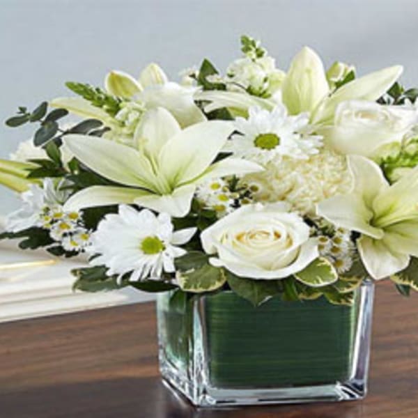 White lilies and roses in a square glass vase