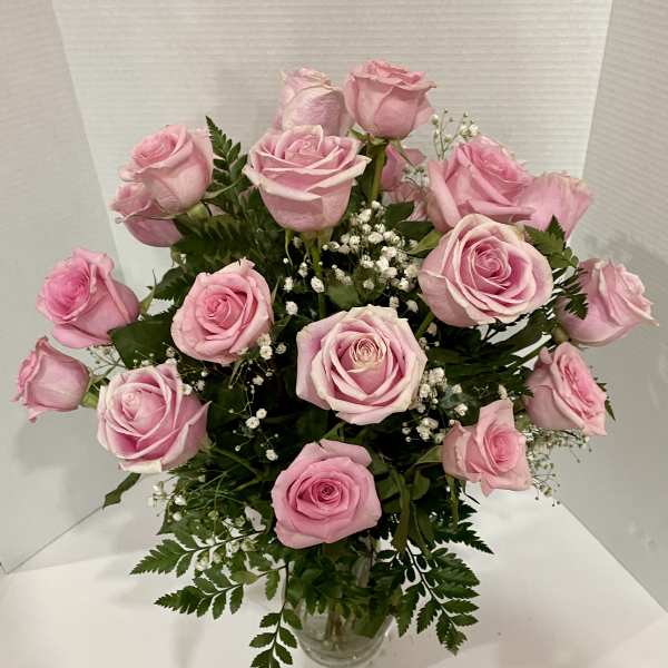 Pink roses arranged in a clear glass vase with baby's breath