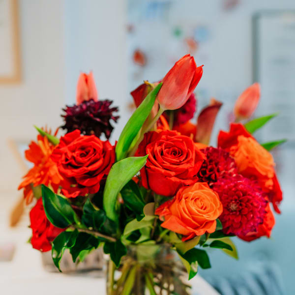 Red and orange flower arrangement in a clear glass vase