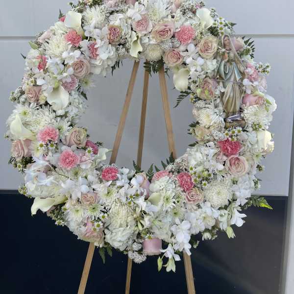Large floral wreath on a wooden easel with pink and white flowers